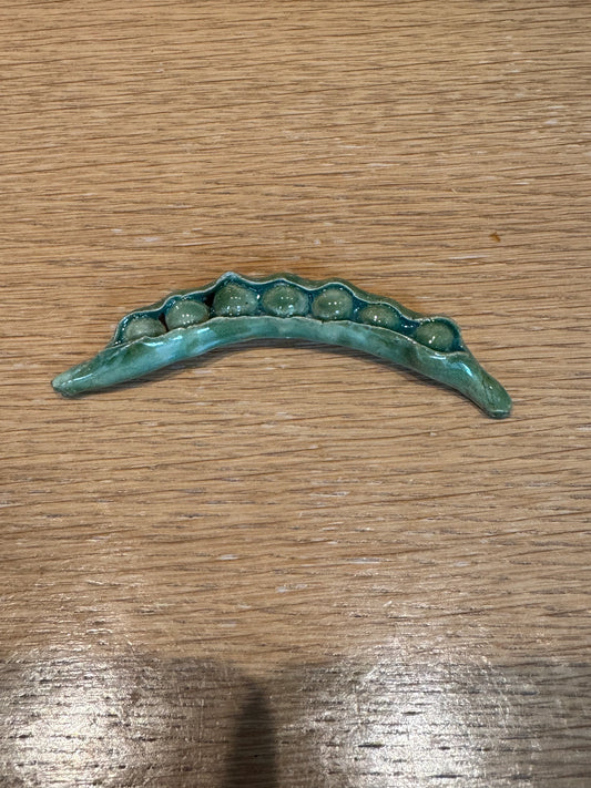 Bronze decorative item shaped like a leaf on a wooden surface, Peas Knife Rest – Handmade Ceramic – Nathalie Reignault Sann
