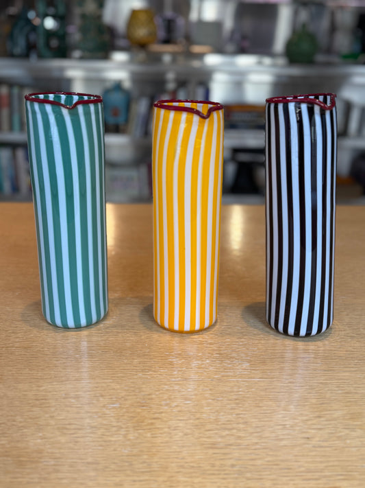 Three striped vases in green, yellow, and black on a wooden surface. Joyful Stripe Pitcher – Murano Glass by France Thierard – Maison Holder