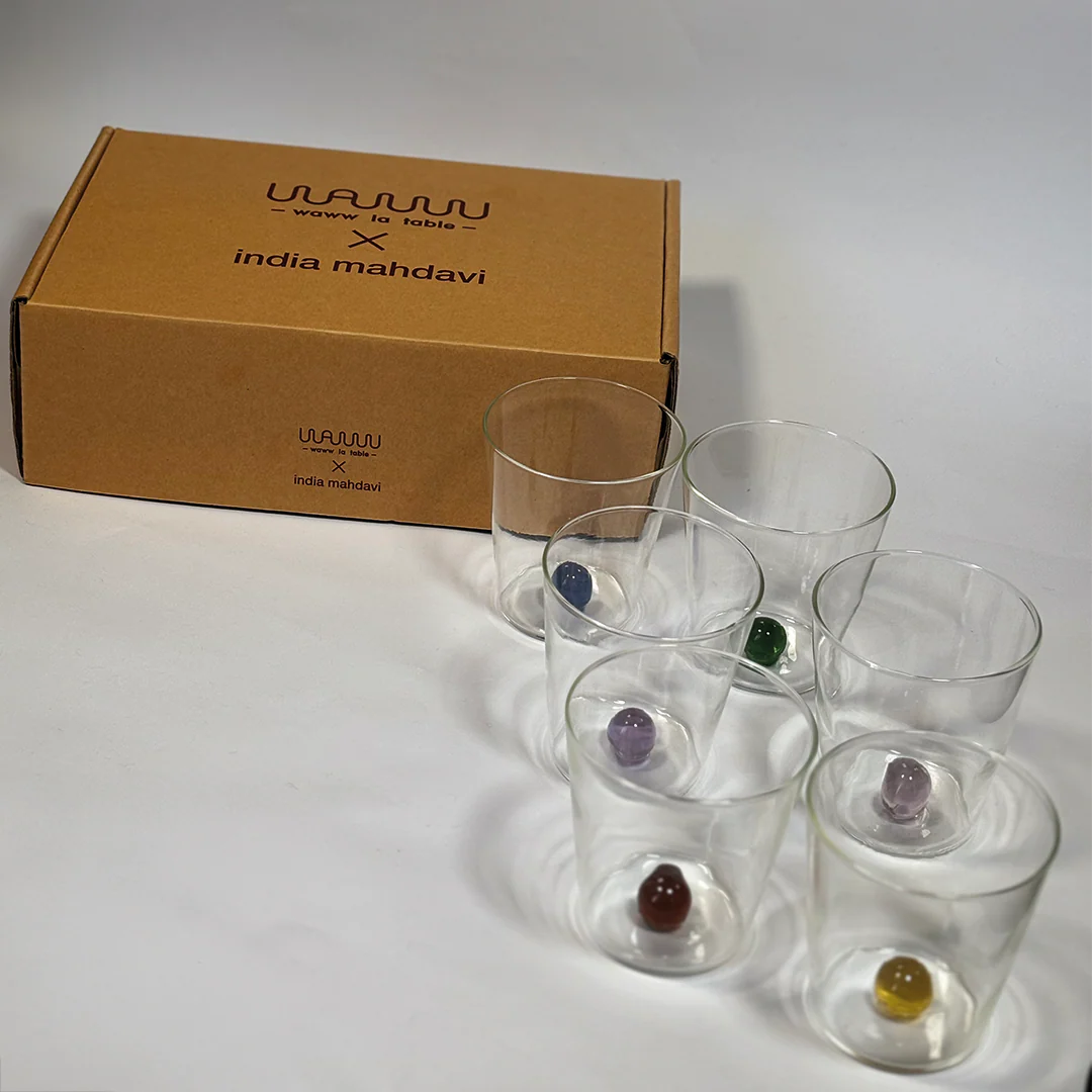 Set of clear glass tumblers with gemstones next to a branded box on a white background, India Mahdavi 6 Glasses & Boule Set – Mouth-Blown Glass – Maison Holder