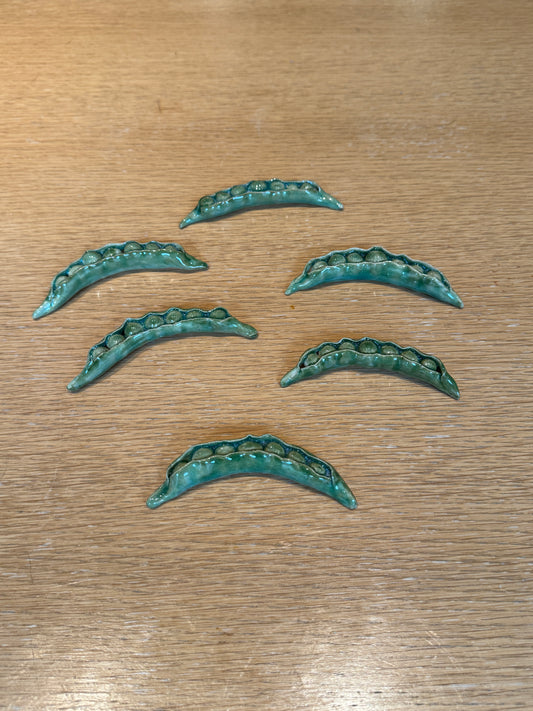 Set of six green metallic decorative elements on a wooden surface, Peas Knife Rest – Handmade Ceramic – Nathalie Reignault Sann