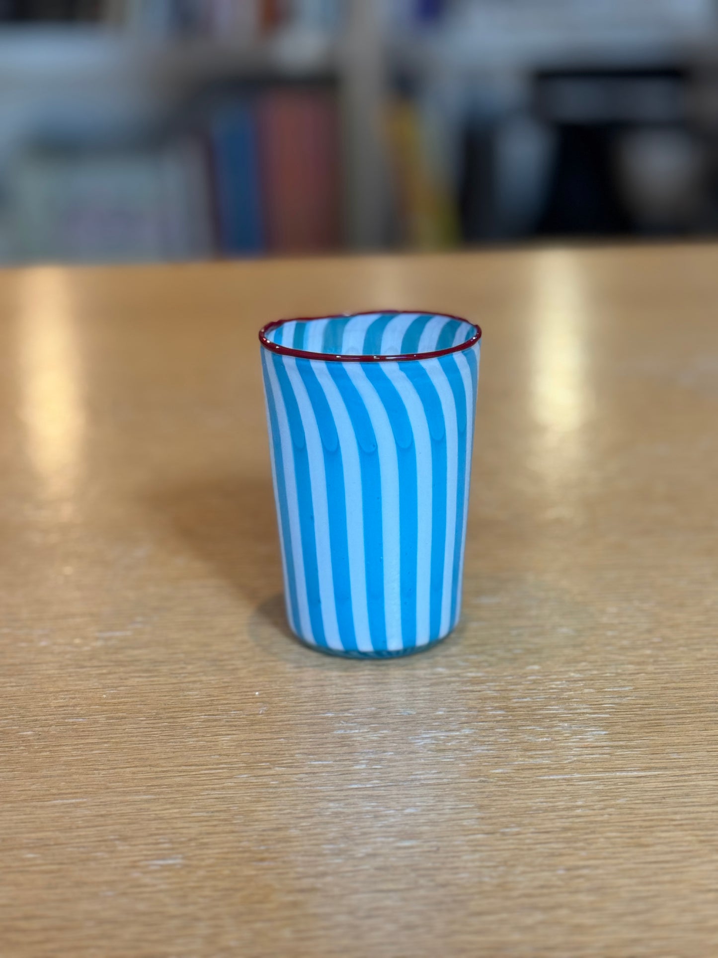 Blue and white striped glass on a wooden surface with a blurred background, Joyful Stripe Glasses – Murano Cane Glassware – Maison Holder