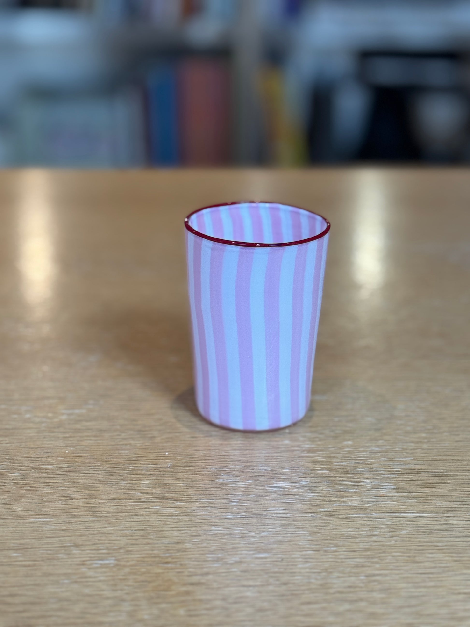 Pink and white striped cup on a wooden surface with a blurred background Joyful Stripe Glasses – Murano Cane Glassware – Maison Holder