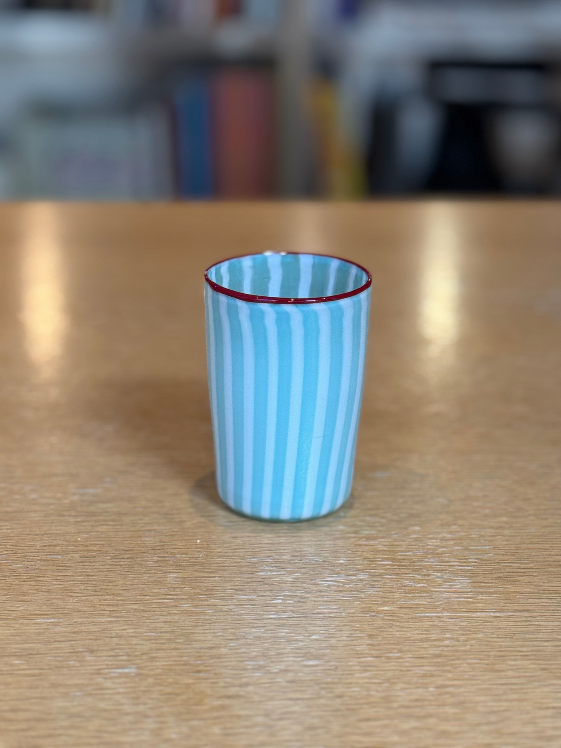 Blue striped glass with red rim on a wooden surface, Joyful Stripe Glasses – Murano Cane Glassware – Maison Holder