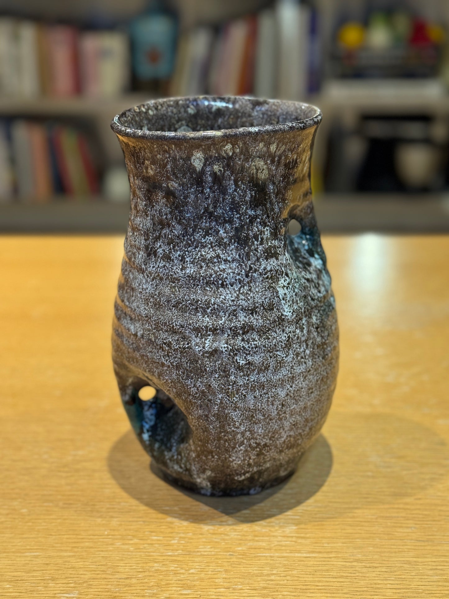 Vintage Vase - Accolay 1960s, Speckled brown and black ceramic vase on a wooden surface with a blurred bookshelf background
