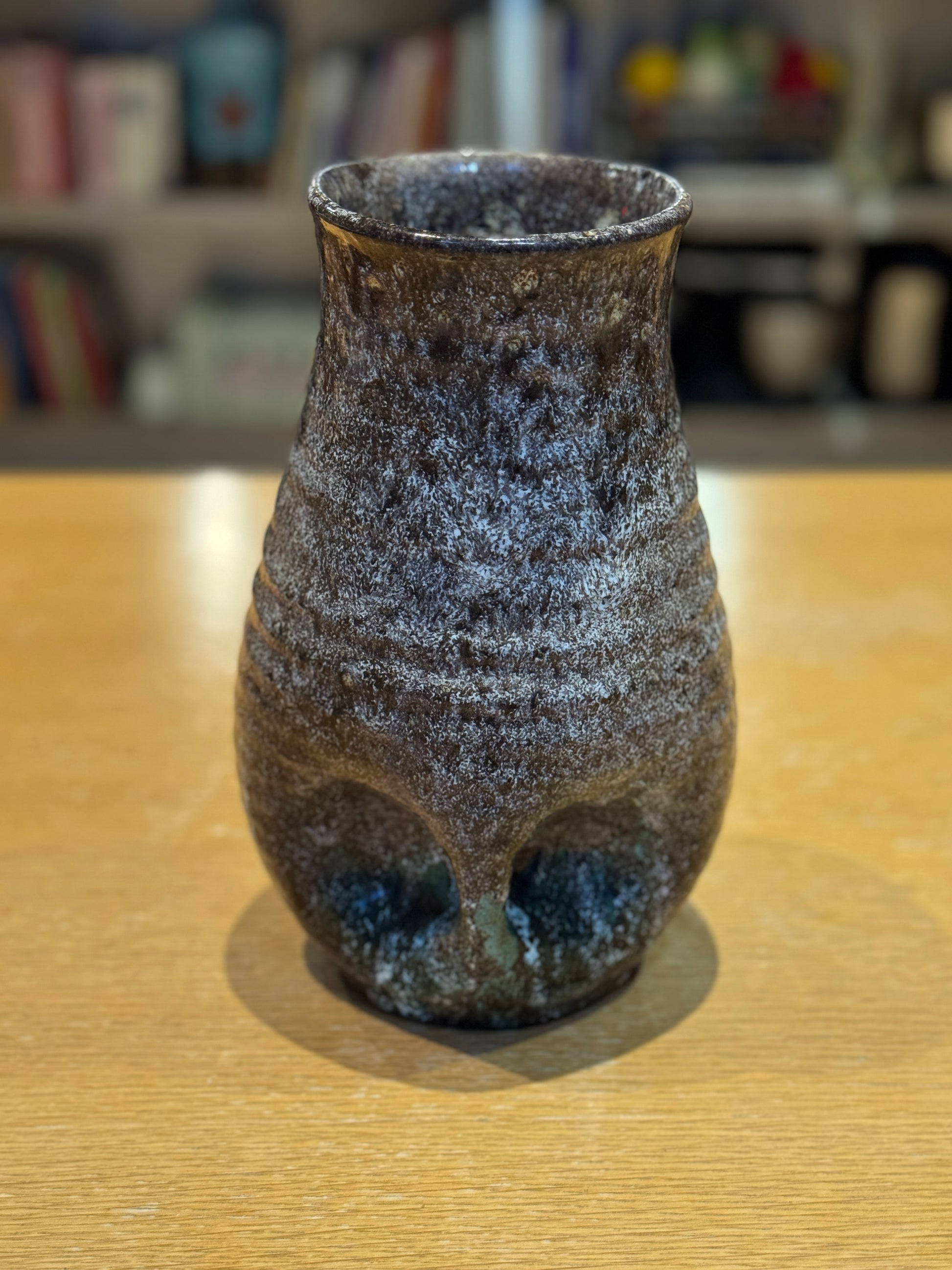 Vintage Vase - Accolay 1960s, Speckled brown and black ceramic vase on a wooden surface with a blurred bookshelf background