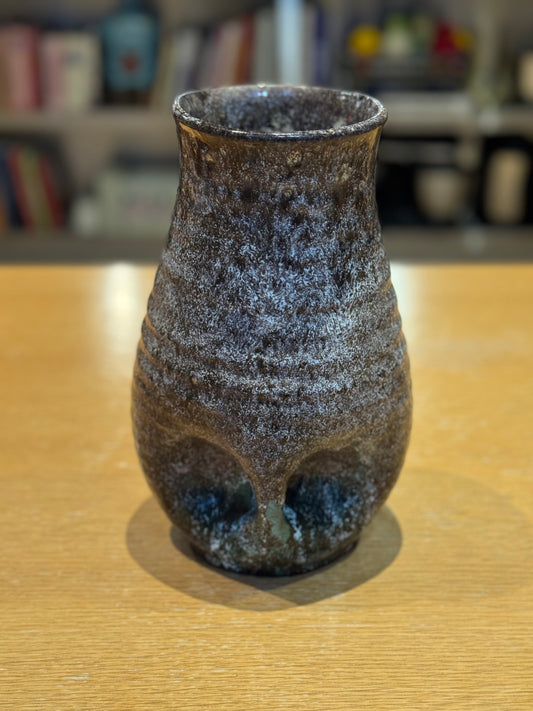 Vintage Vase - Accolay 1960s, Speckled brown and black ceramic vase on a wooden surface with a blurred bookshelf background