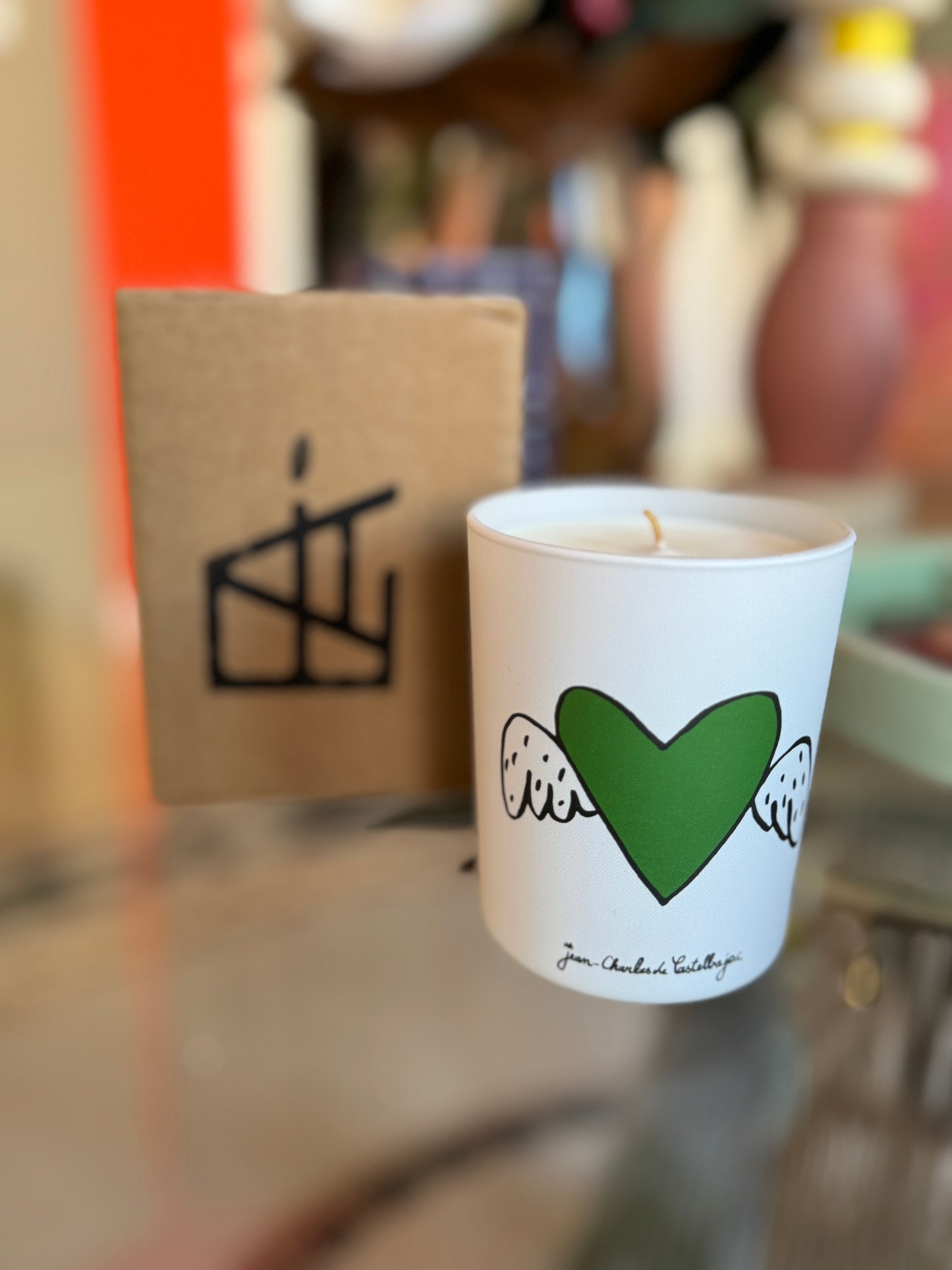 White cup with green heart design on a blurred background, Jean-Charles de Castelbajac Art Candle – Épreuve d’Artistes – Maison Holder