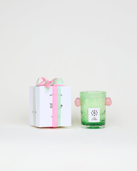 Green glass candle with pink handles and a gift box with a pink ribbon on a white background, Peony Candle Luberon Lime Blossom – La Romaine Editions – Maison Holder