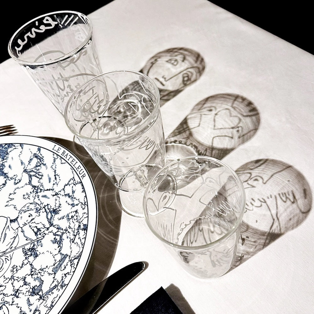 Set of engraved glasses on a white surface with artistic illustrations. Jean-Charles de Castelbajac Colombes Wine Glass – WAWW