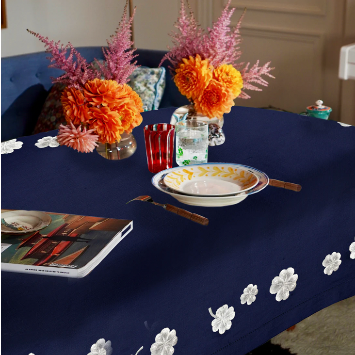 Navy blue tablecloth with white floral patterns on a dining table set with flowers and cutlery. Lucky Star Linen Napkin – Hand Embroidered – Maison Holder