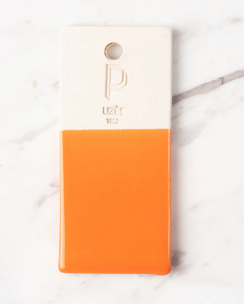 Notebook with a white top half and orange bottom half on a marble surfacem Meleia Service Flat Plate – Handmade Ceramic – Maison Pichon