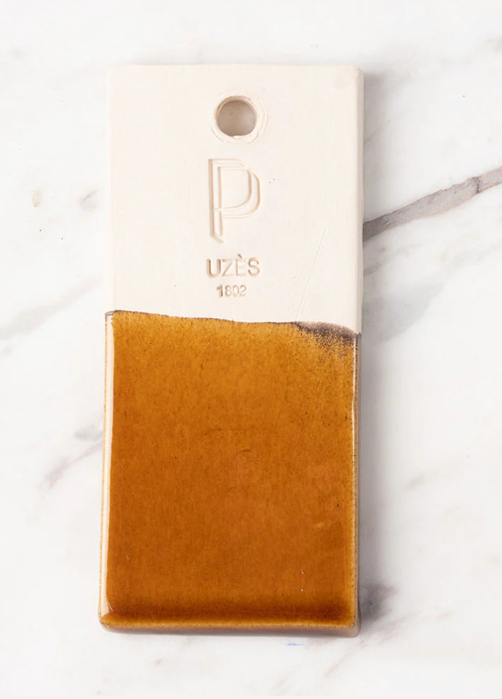 Brown leather wallet with 'puès' branding on a white marble surface,  Lisa Iconic Basket – Handmade Ceramic – Maison Pichon