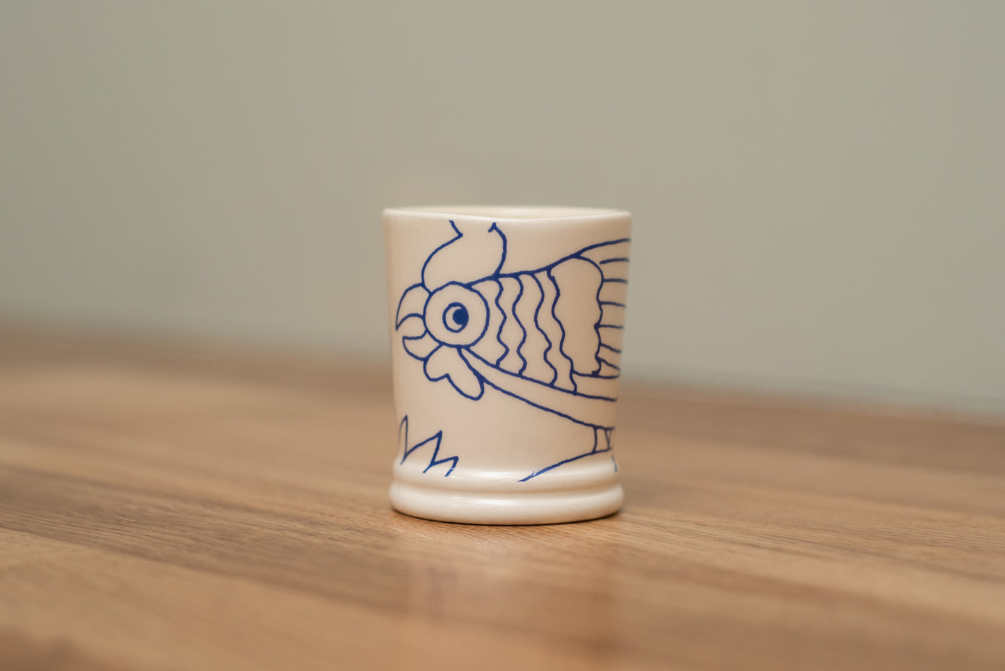 Small ceramic cup with a fish design on a wooden surface, Rouen Decor Espresso Cup – Desvres Earthenware – Maison Holder