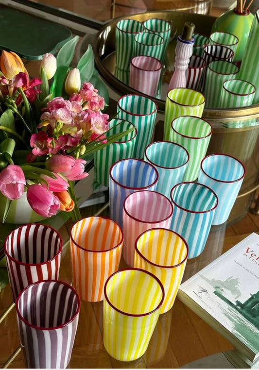 Colorful striped glasses on a table with flowers and a magazine. Joyful Stripe Glasses – Murano Cane Glassware – Maison Holder