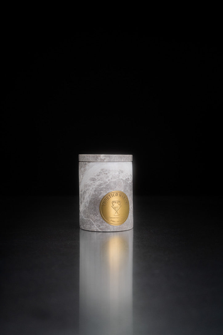Candle in a decorative container with a gold emblem on a dark background Salina Marble Candle – Maison Holder Luxury Scented Marble