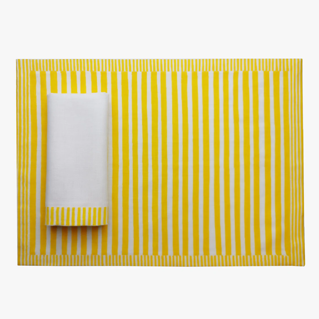 Yellow and white striped placemat with a folded white napkin on a white background, Milleraies Striped Linen Placemat – Aurelie Bidermann – Maison Holder