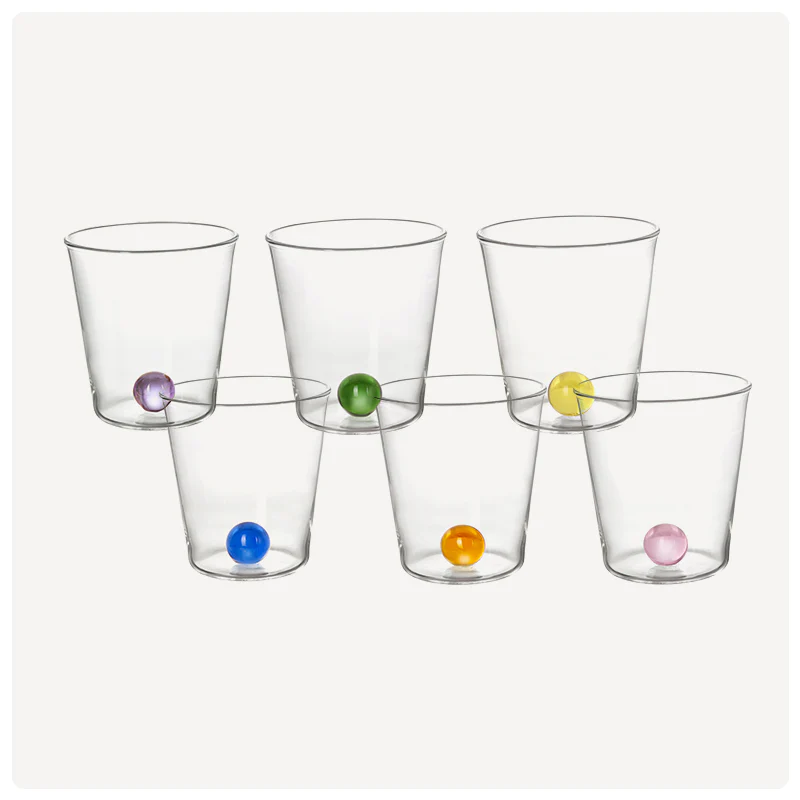 Set of six clear glasses with colorful marbles on a white background, India Mahdavi 6 Glasses & Boule Set – Mouth-Blown Glass – Maison Holder