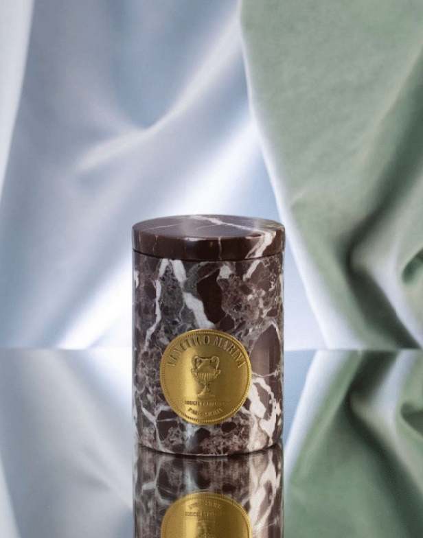 Marble-patterned cylindrical container with a gold emblem on a reflective surface, Lipari Marble Candle – Venetico Marina – Maison Holder