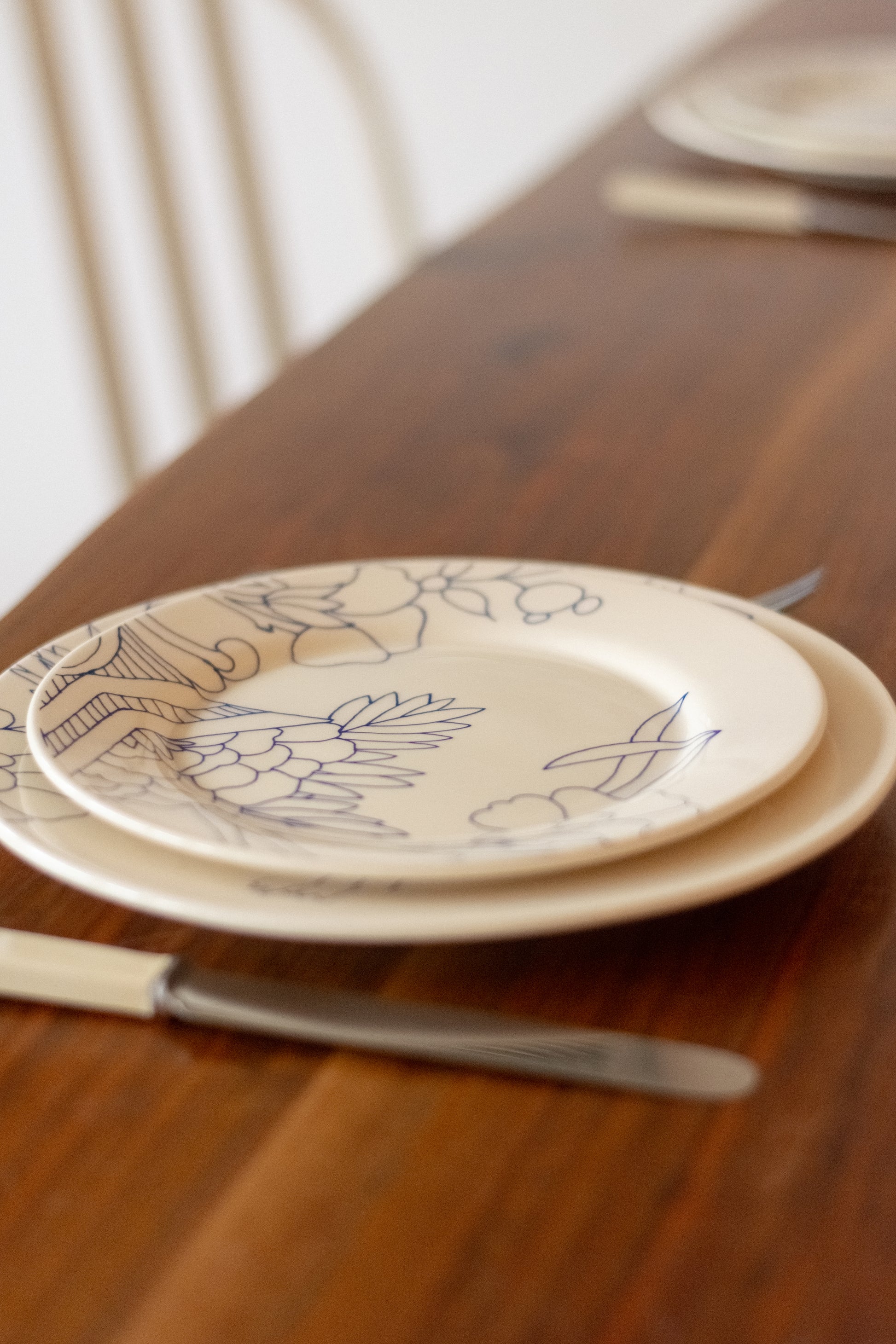 Two ceramic plates with floral designs on a wooden table. Dessert Plate Rouen Decor – Desvres Earthenware – Maison Holder