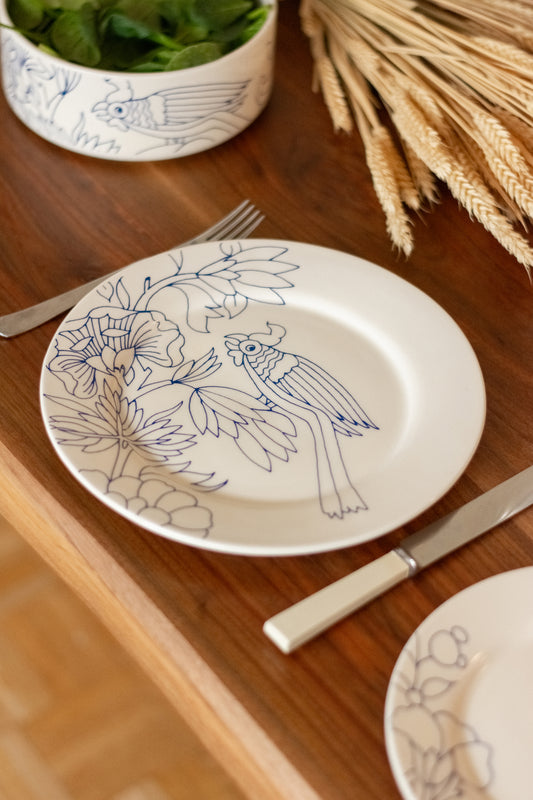 Decorative plate with bird and floral design on a wooden table with cutlery and a bowl. Dinner Plate Rouen Decor – Desvres Earthenware – Maison Holder