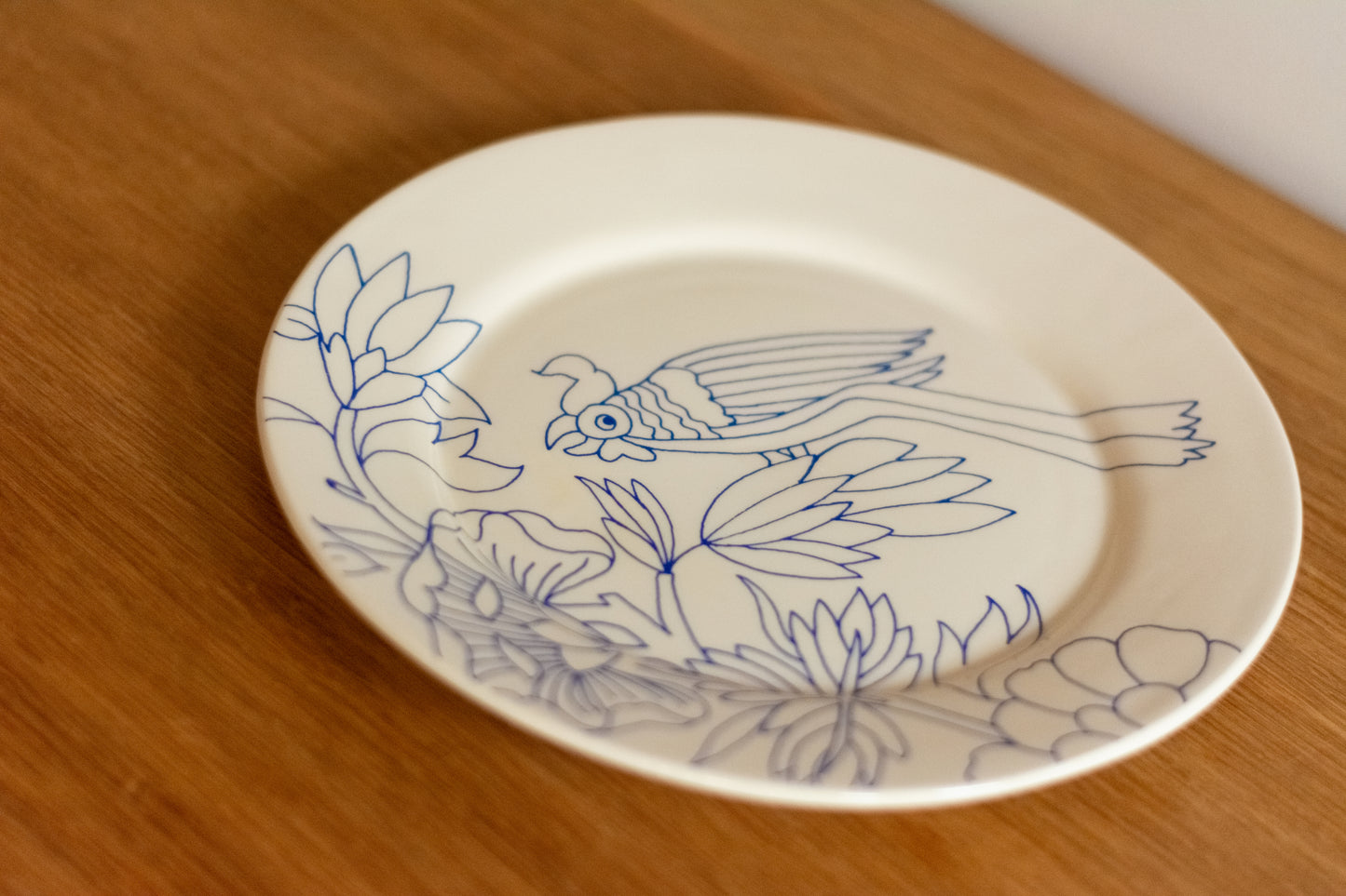 White plate with blue floral and bird design on a wooden surface, Dinner Plate Rouen Decor – Desvres Earthenware – Maison Holder