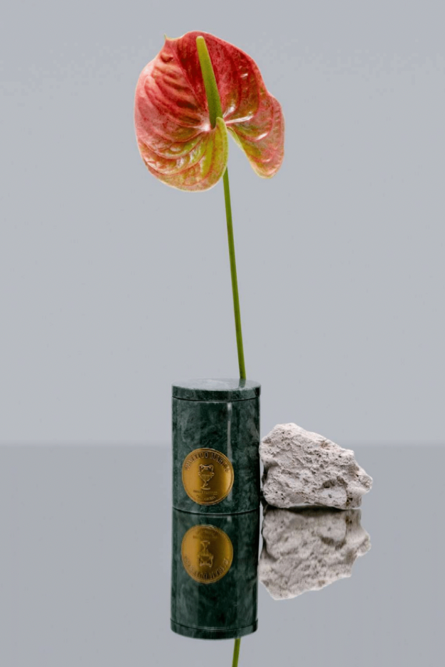 Green marble vase with gold emblem holding a red and yellow flower against a gray background, Tindari Marble Candle – Venetico Marina – Maison Holder