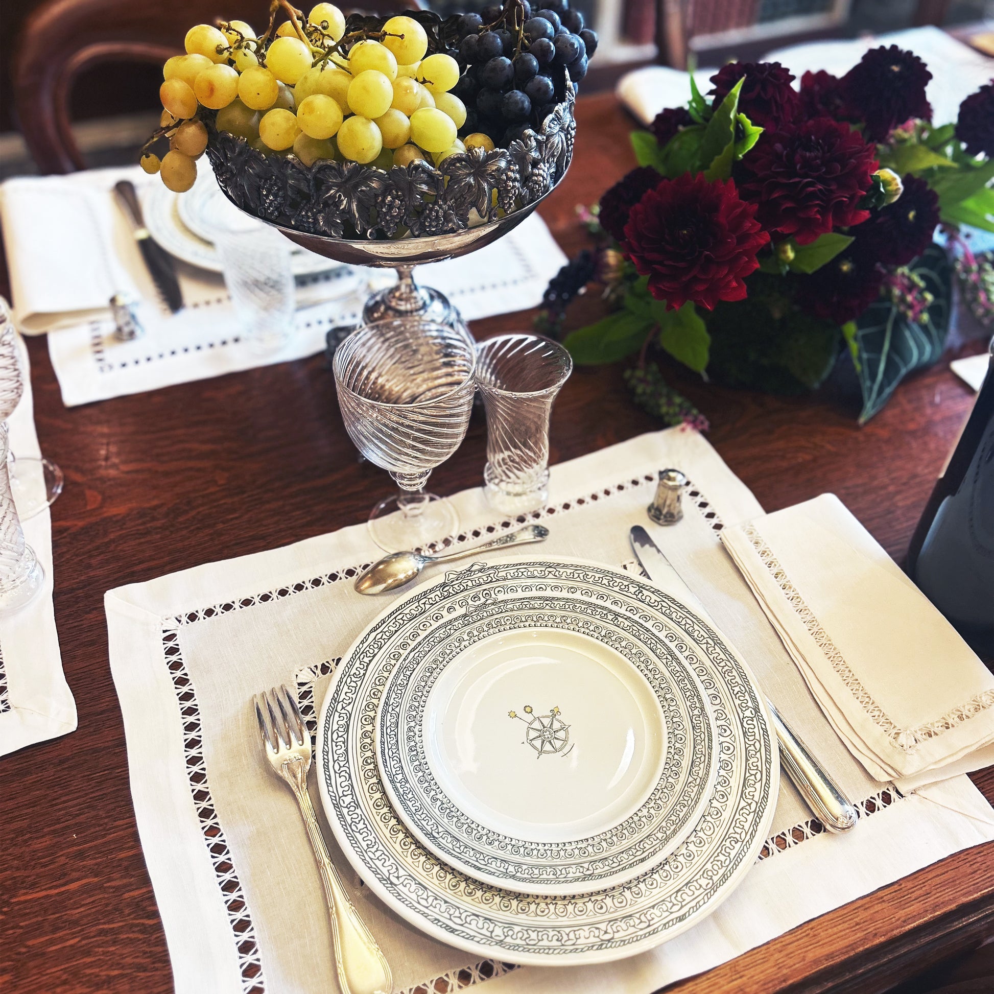 Elegant table setting with decorative plates, silverware, and a fruit bowl on a wooden table. Château Set of 6 Small Plates – Limoges Porcelain – Maison Holder