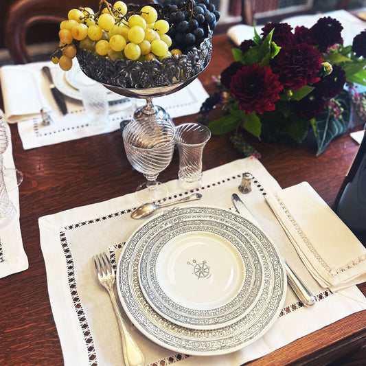 Elegant table setting with decorative plates, silverware, and a fruit bowl on a wooden table. Château Set of 6 Small Plates – Limoges Porcelain – Maison Holder