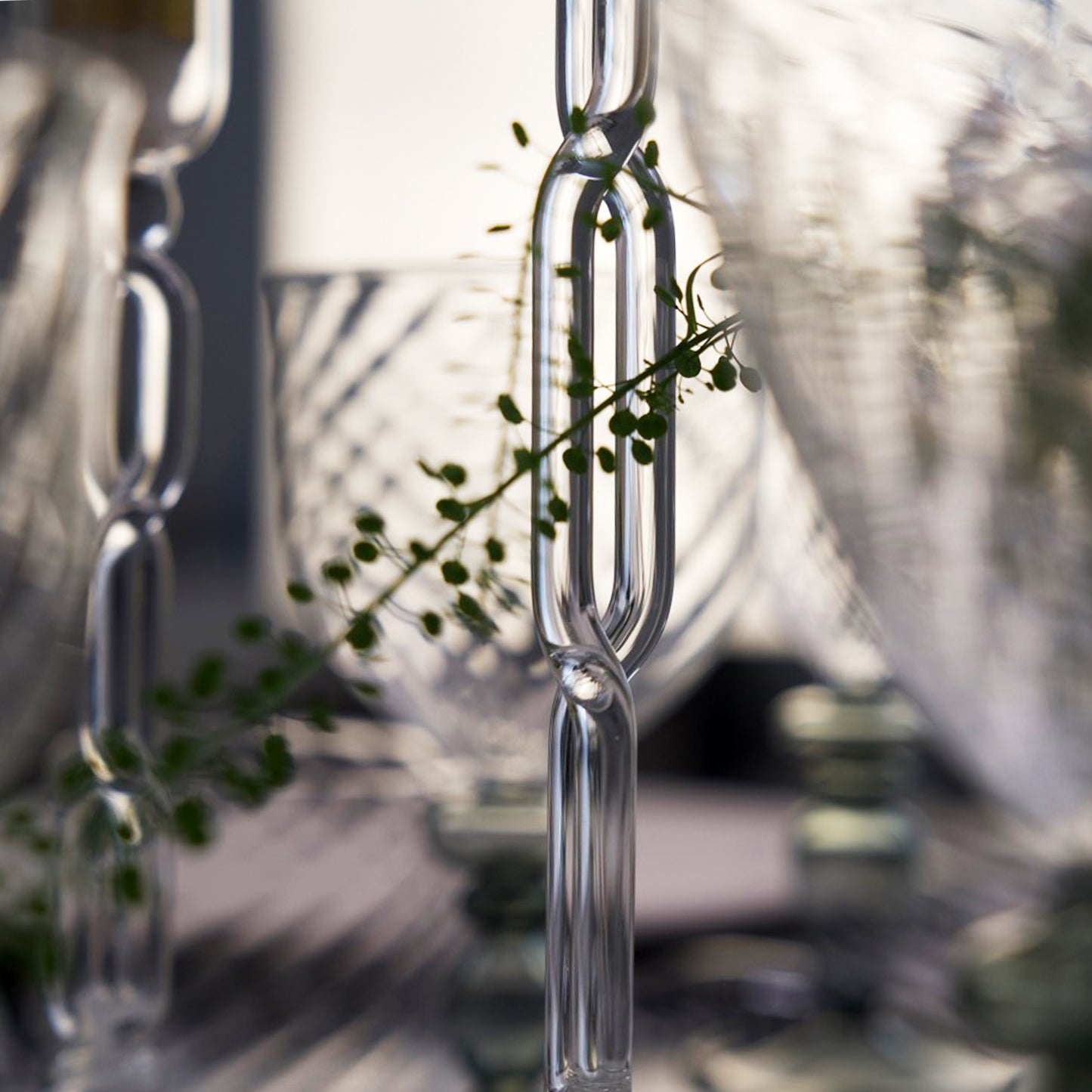 Clear glass hanging plant holder with green leaves against a blurred outdoor background, Infinity Large Candle Holder – Sculptural Glass Art – Maison Holder