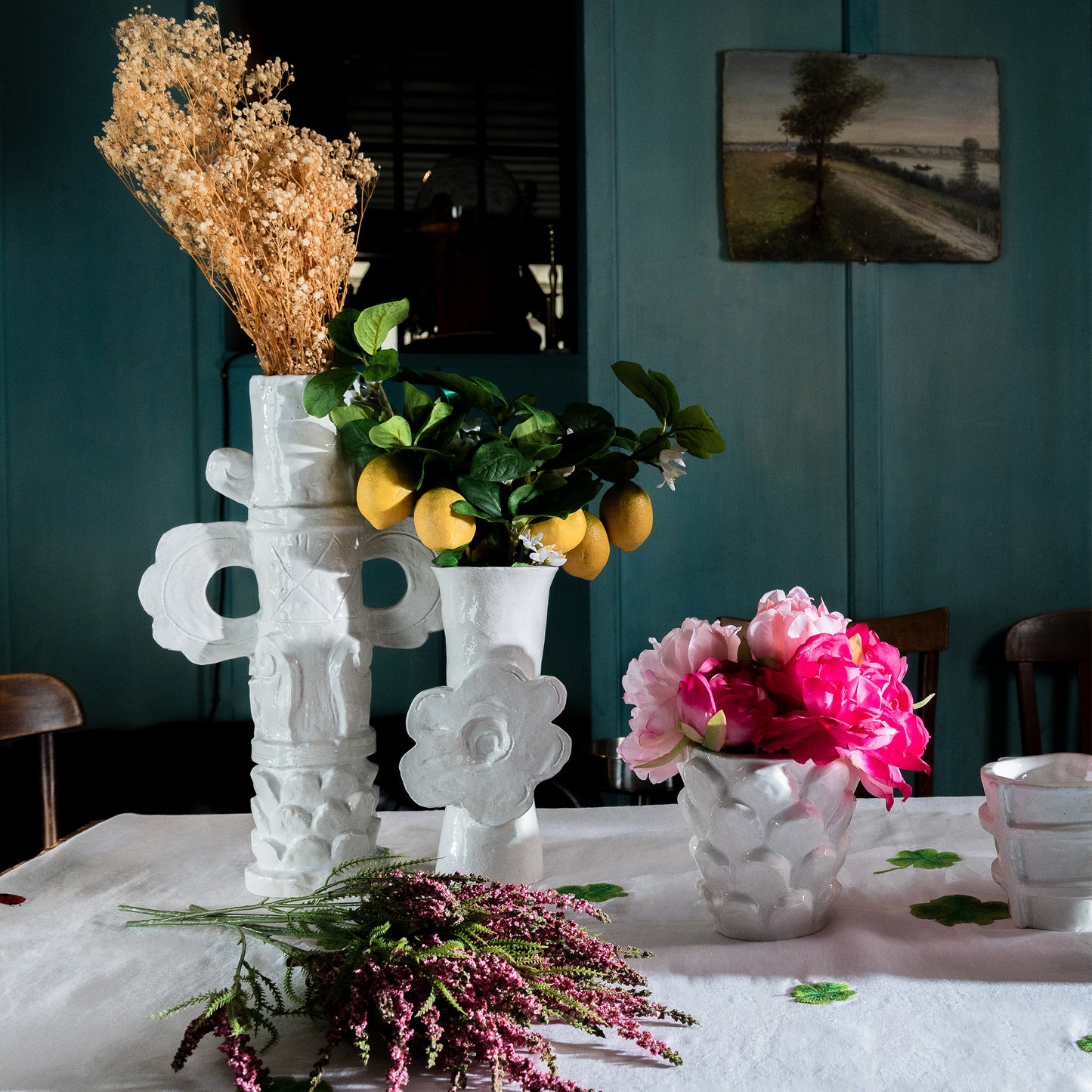 Decorative table setting with white vases containing flowers and plants against a teal wall. Bela Silva Girandoles Flower Power Vase – Terracotta – WAWW

