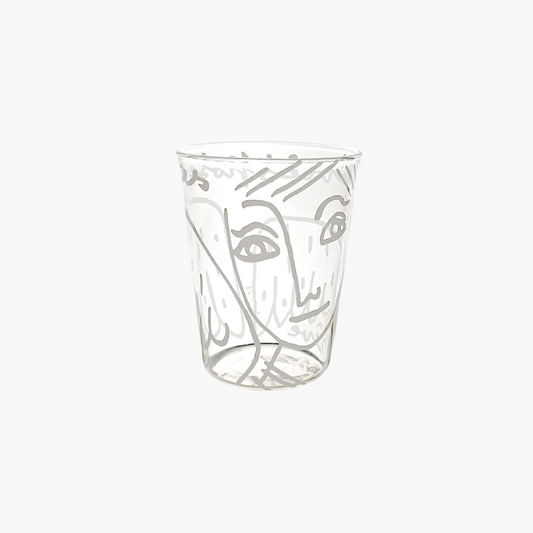 Clear glass tumbler with artistic face design on a white background , Jean-Charles de Castelbajac Angel Tumbler – WAWW